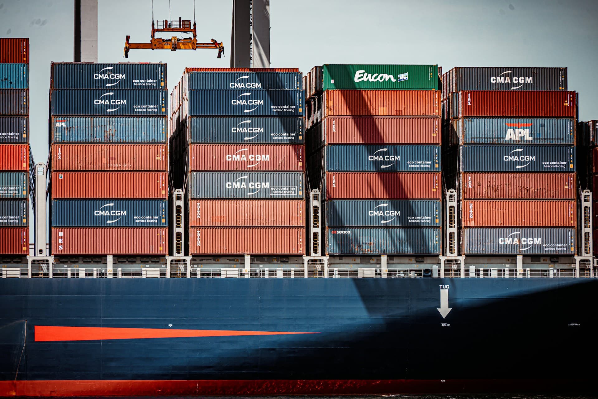 Stacked shipping containers loaded on a container vessel under a gantry crane