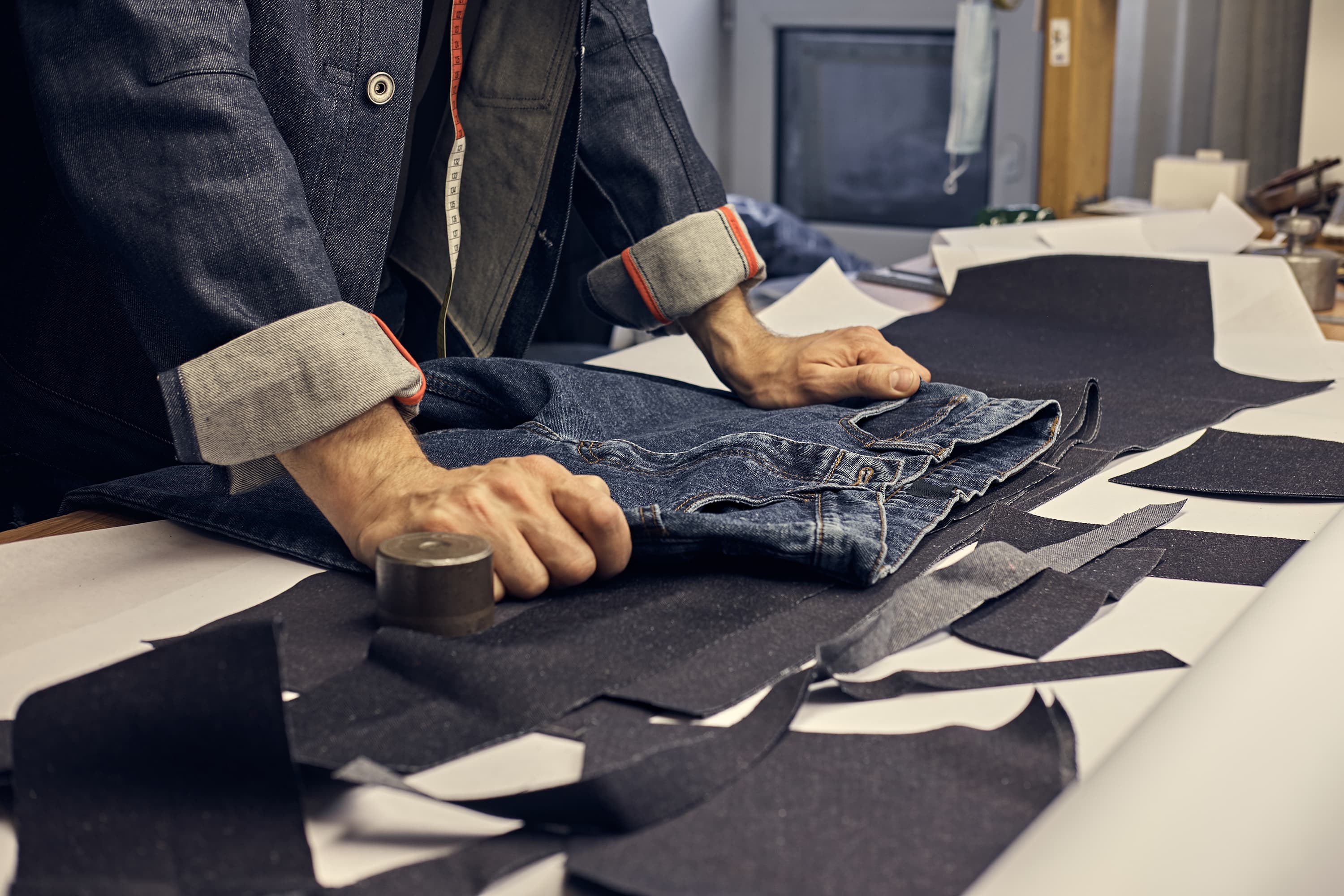 Inspector checking a pair of jeans against cut denim panels on the cutting table