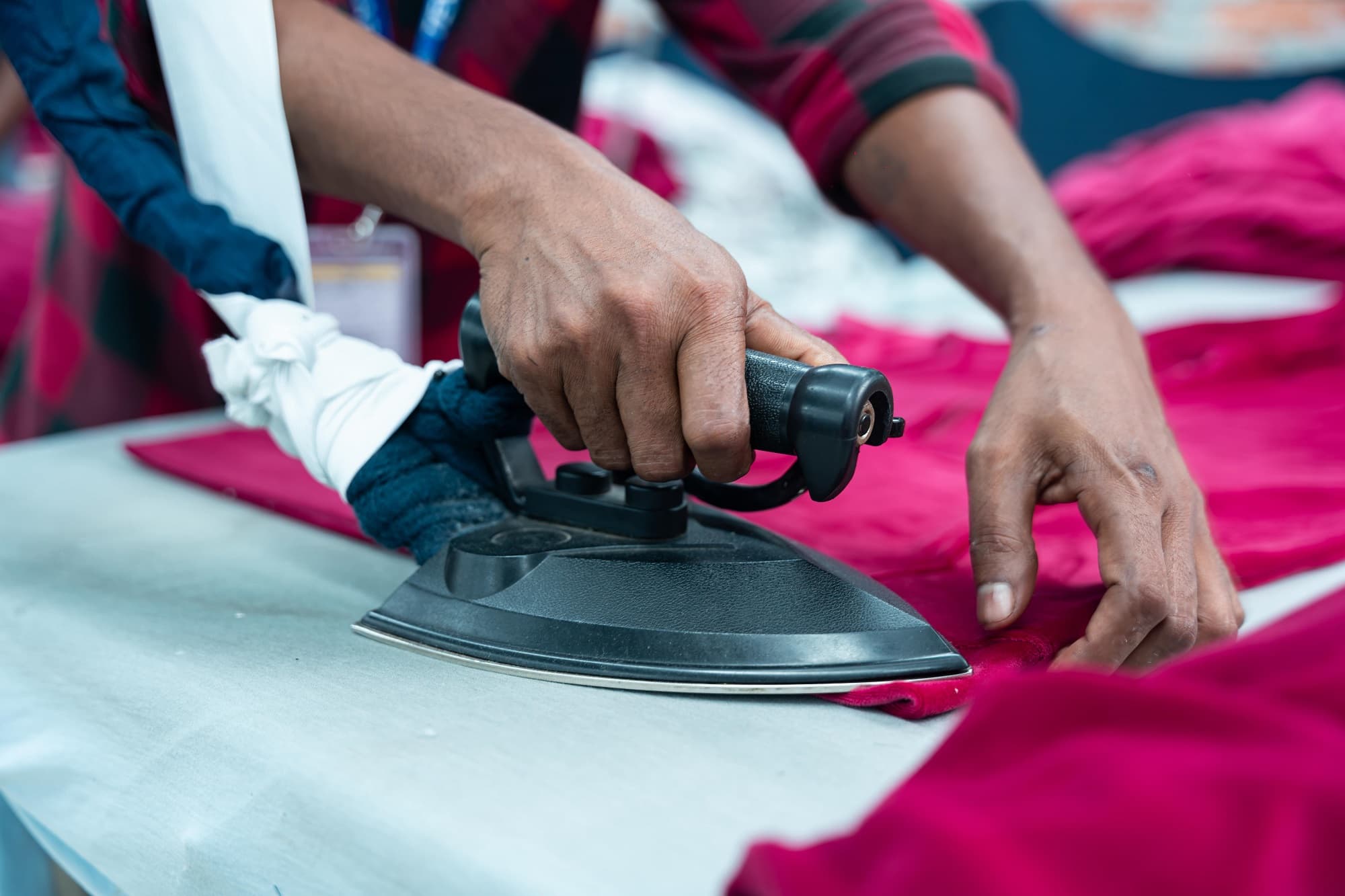 Finisher pressing a magenta garment with a steam iron