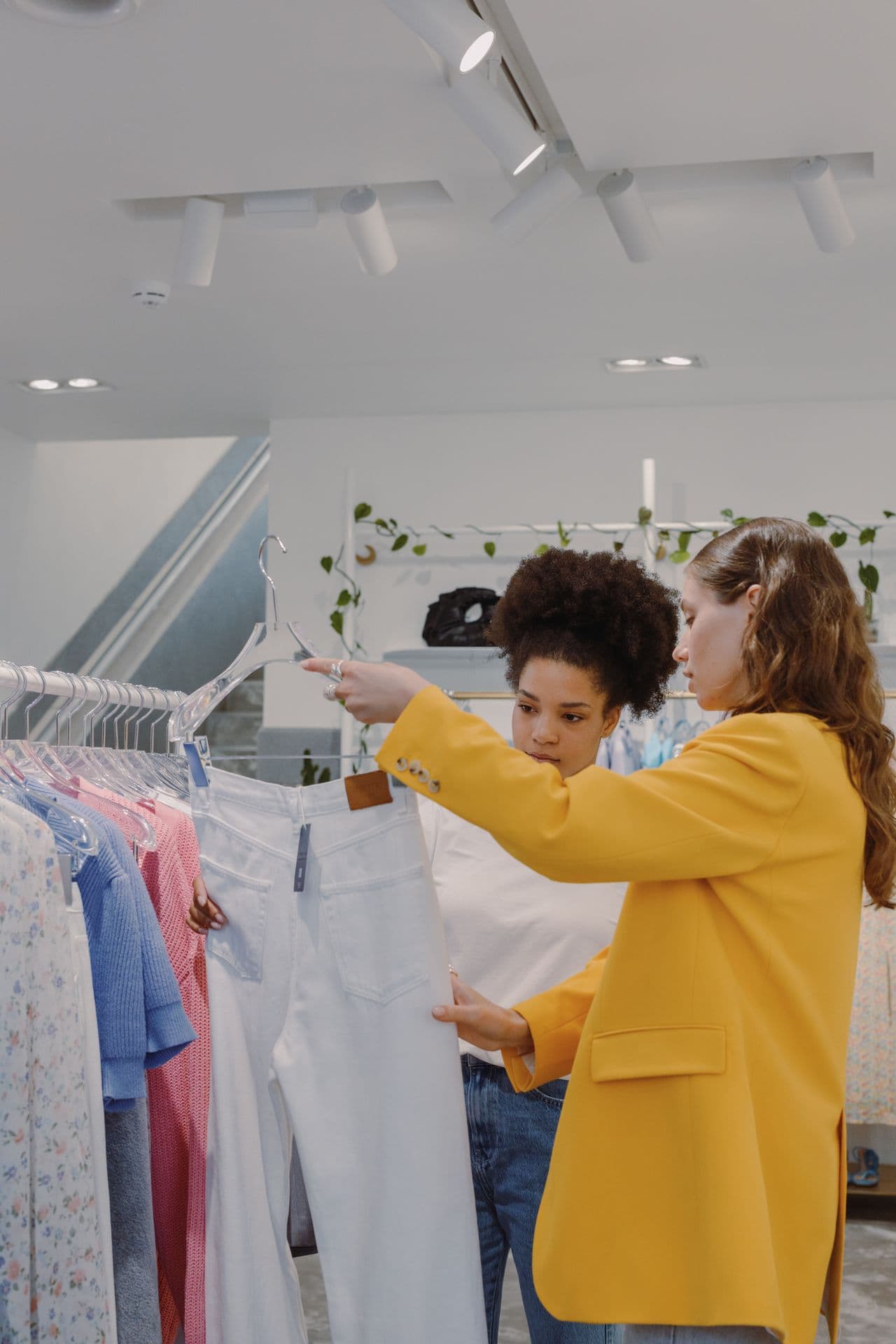 Two buyers reviewing a pair of white trousers on a showroom rail