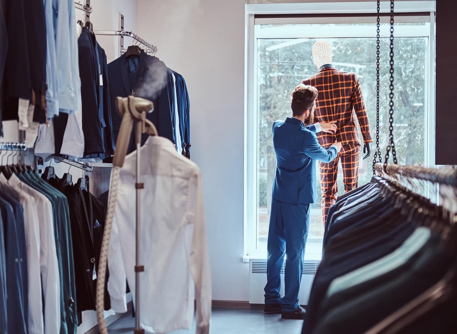 Retailer styling a mannequin in a checked suit on the shop floor