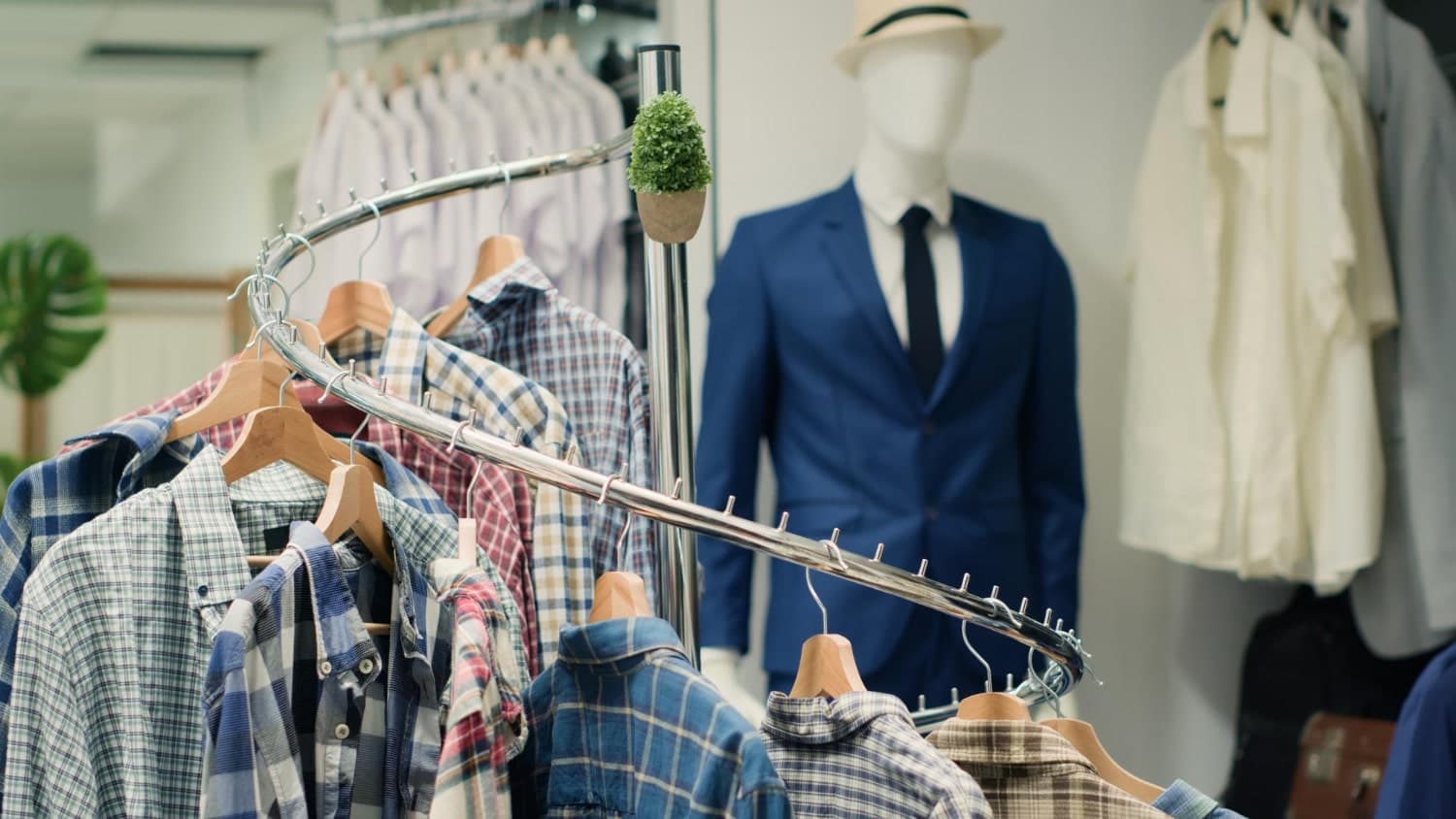 Checked shirts on a curved rail with a suited mannequin behind