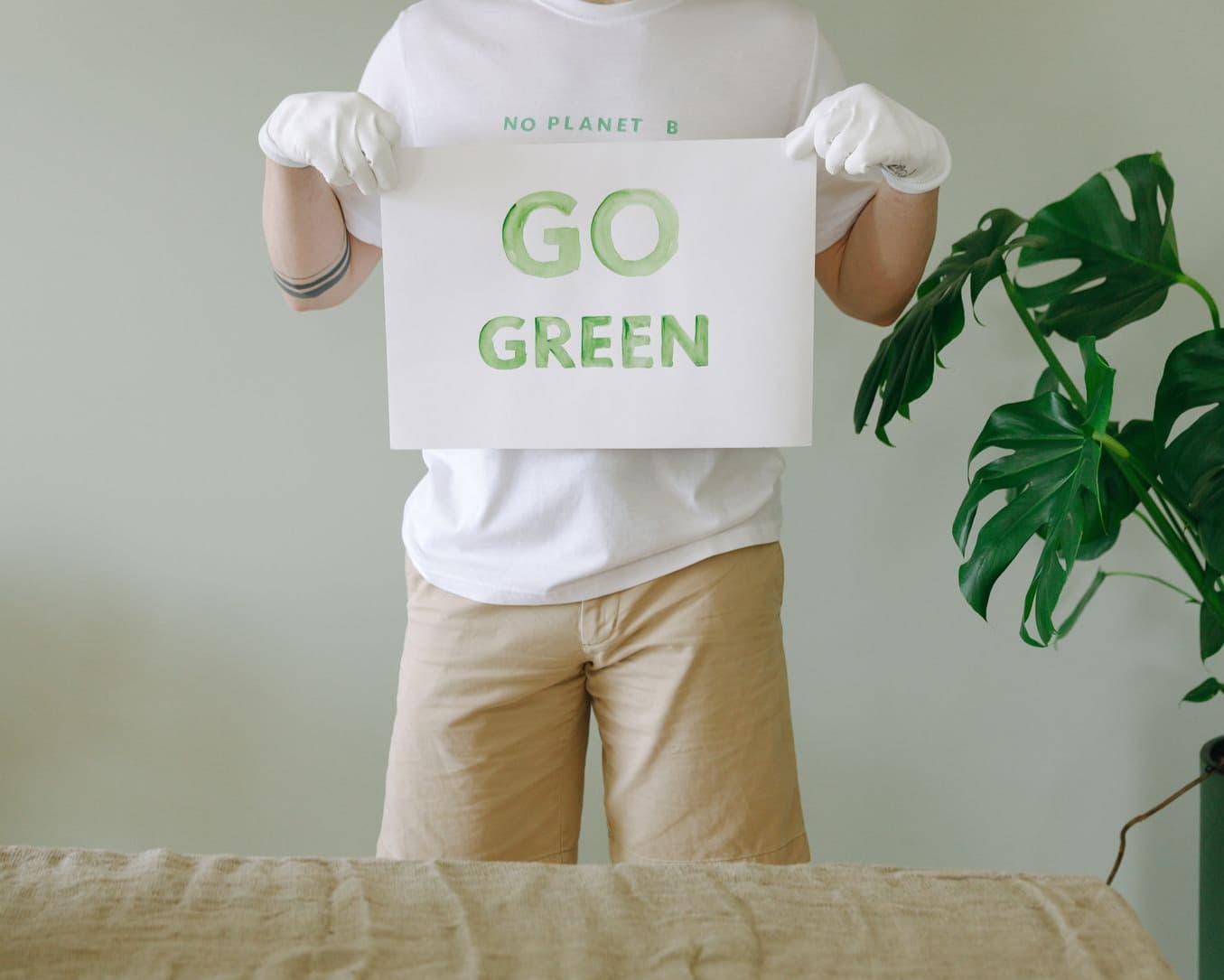 A person in gloves holding a hand-painted "Go Green" placard